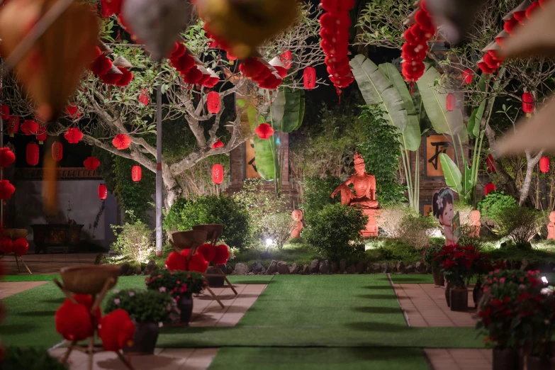 a garden filled with lots of plants and red lanterns hanging from the ceiling