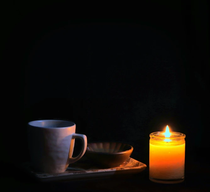 a lit candle and mug sitting on a tray