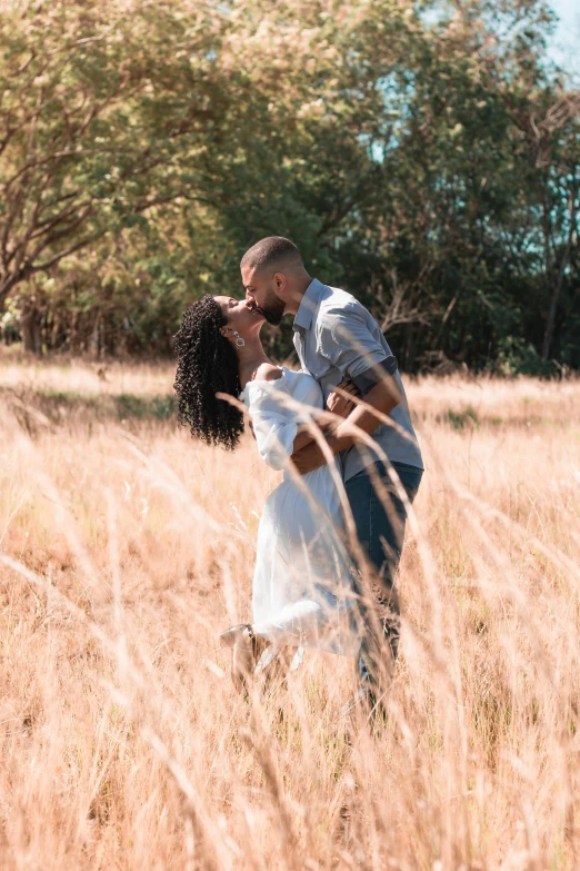 a man and a woman kissing in a field of tall grass