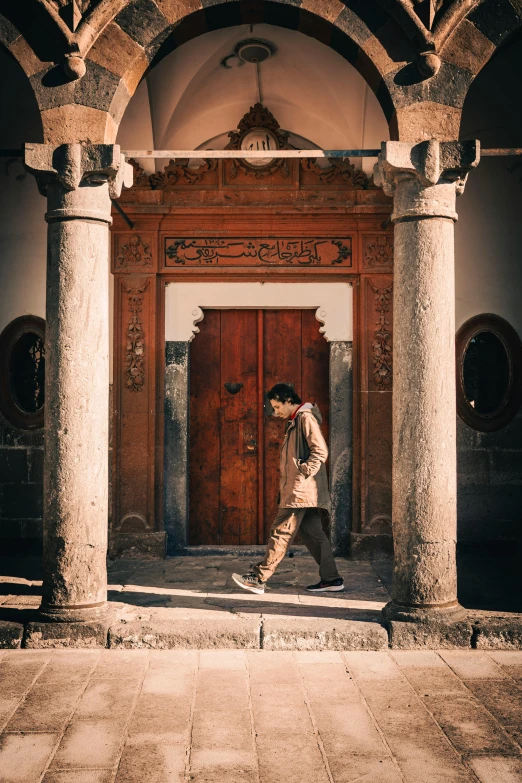 a man walking past a very large wooden door