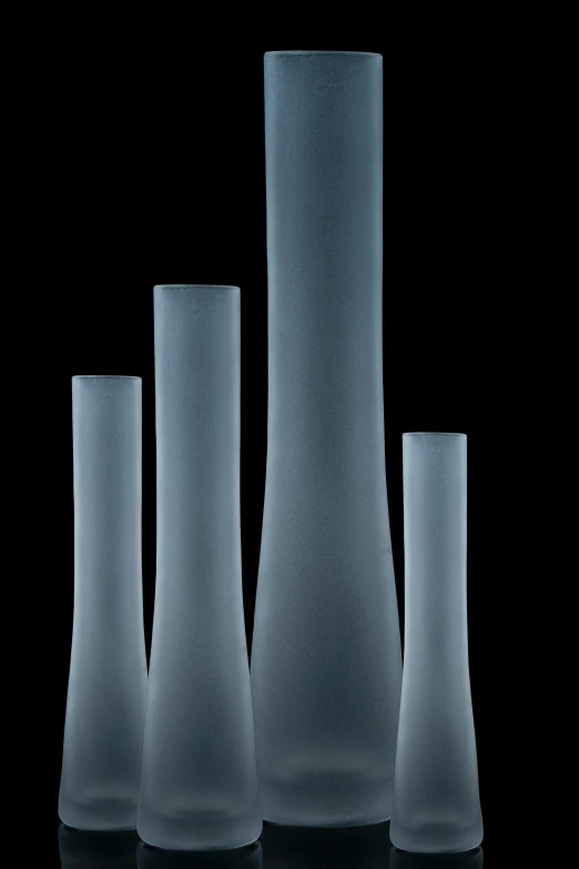 a group of three glass vases against a black background