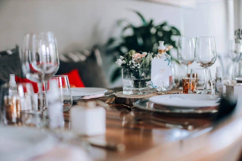 a dining table with white dishes and flowers on top