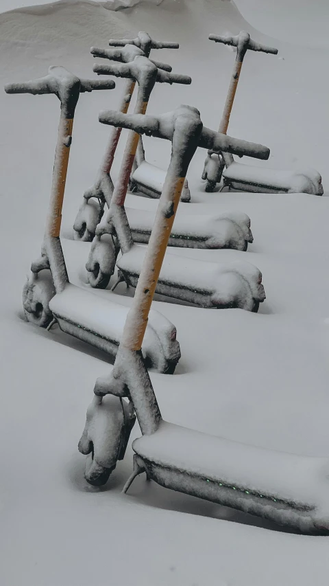 row of parked scooters covered in snow