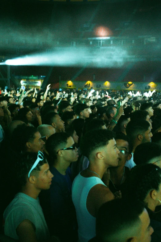 many people are standing together while looking up at the stage