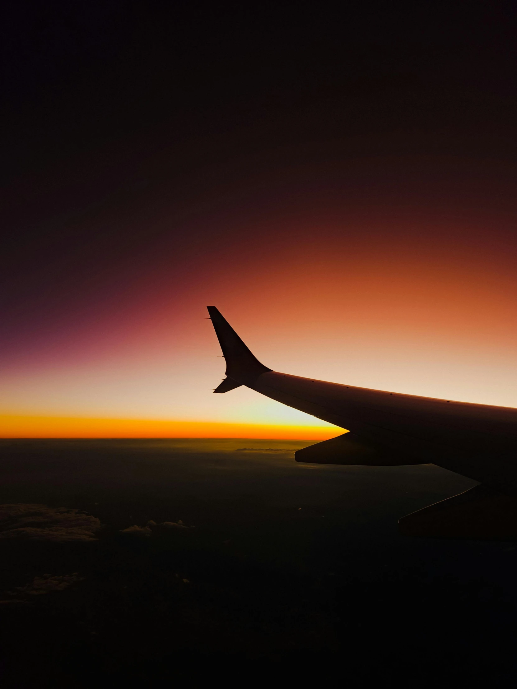 the wing of an airplane in the sunset sky