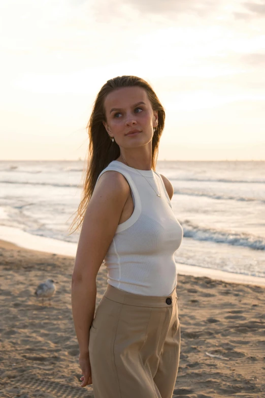 a woman standing on the beach, wearing pants