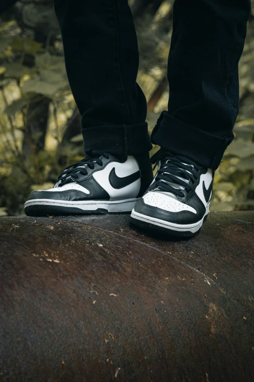 a person wearing sneakers standing on a log