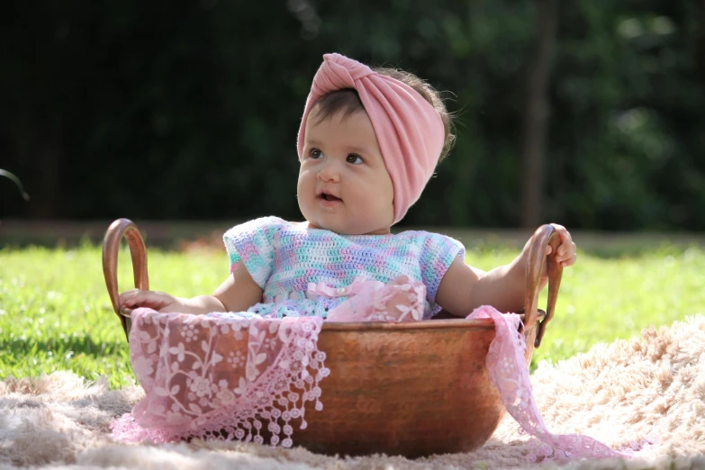 baby girl in an old basket wearing a pink turban