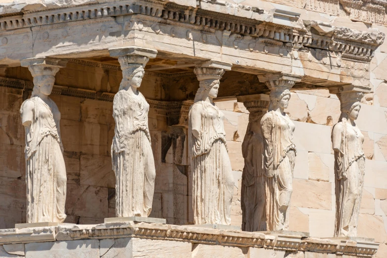 four antique statues on a very tall stone structure