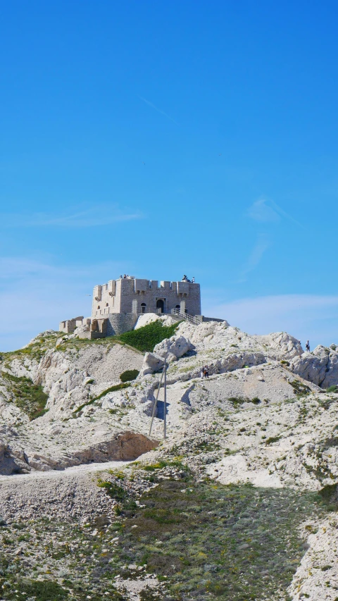 a castle atop a rocky hill with some grass