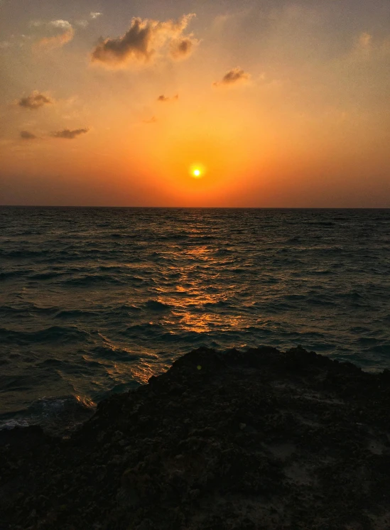 the sun is rising over the ocean at sunset