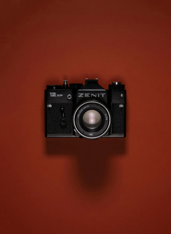 an old analog camera on red wall background