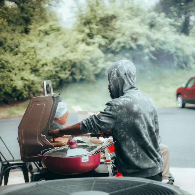 the man is sitting outside cooking on his motorcycle