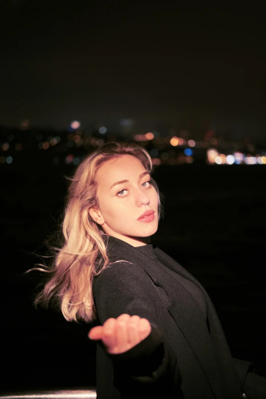 a young blonde woman in a black top on the water at night