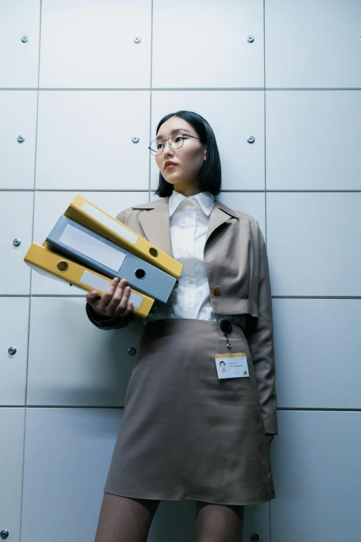 a young woman standing next to a white wall holding some boxes