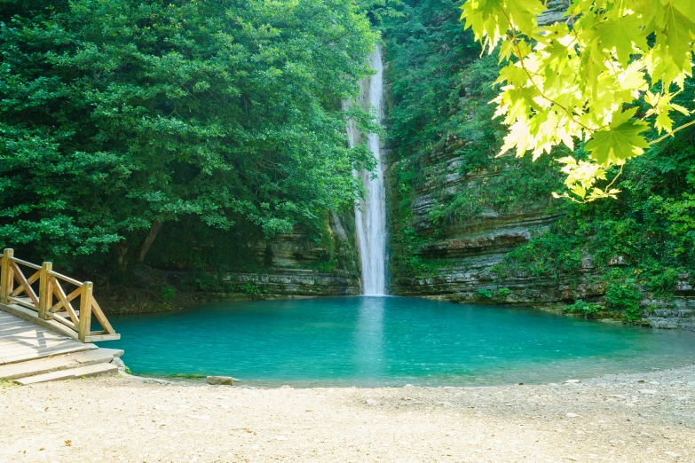 a person sitting at a small bench near a waterfall