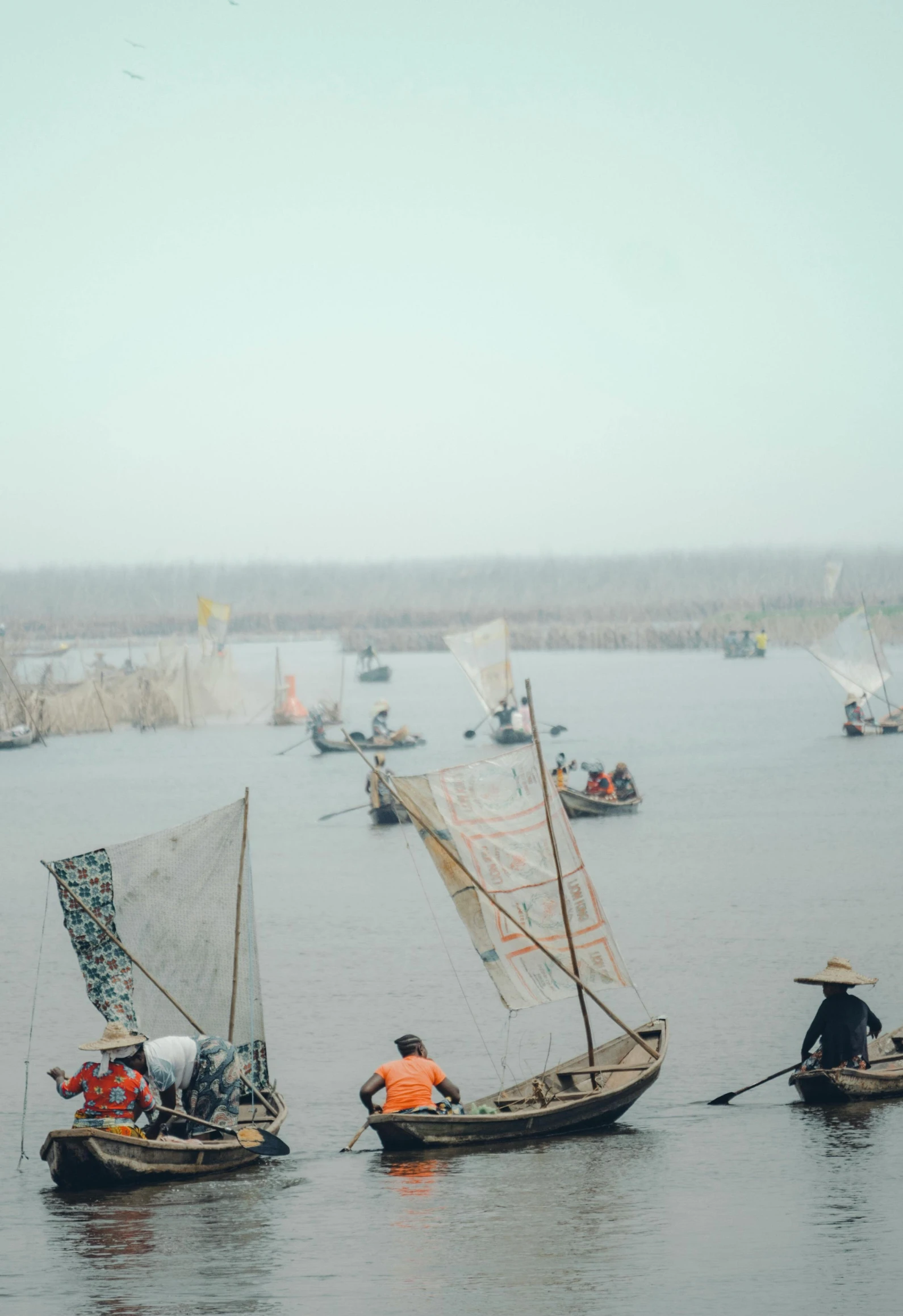 several boats with sails in the water with flags