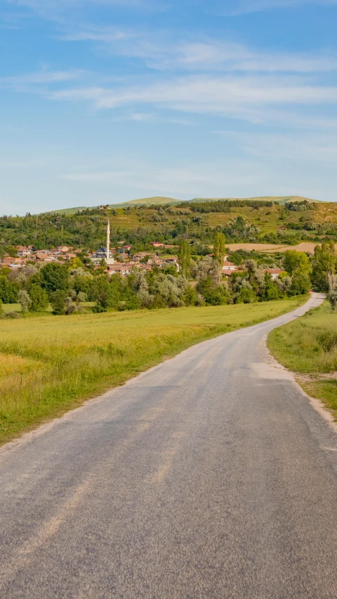 a rural highway with a stop sign in the foreground and an out door town in the distance