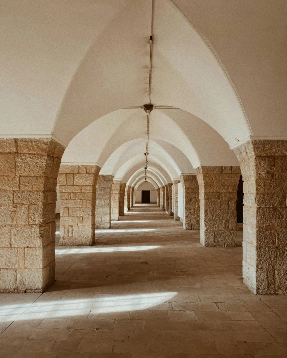 a long passageway in an empty building with pillars leading into the exit