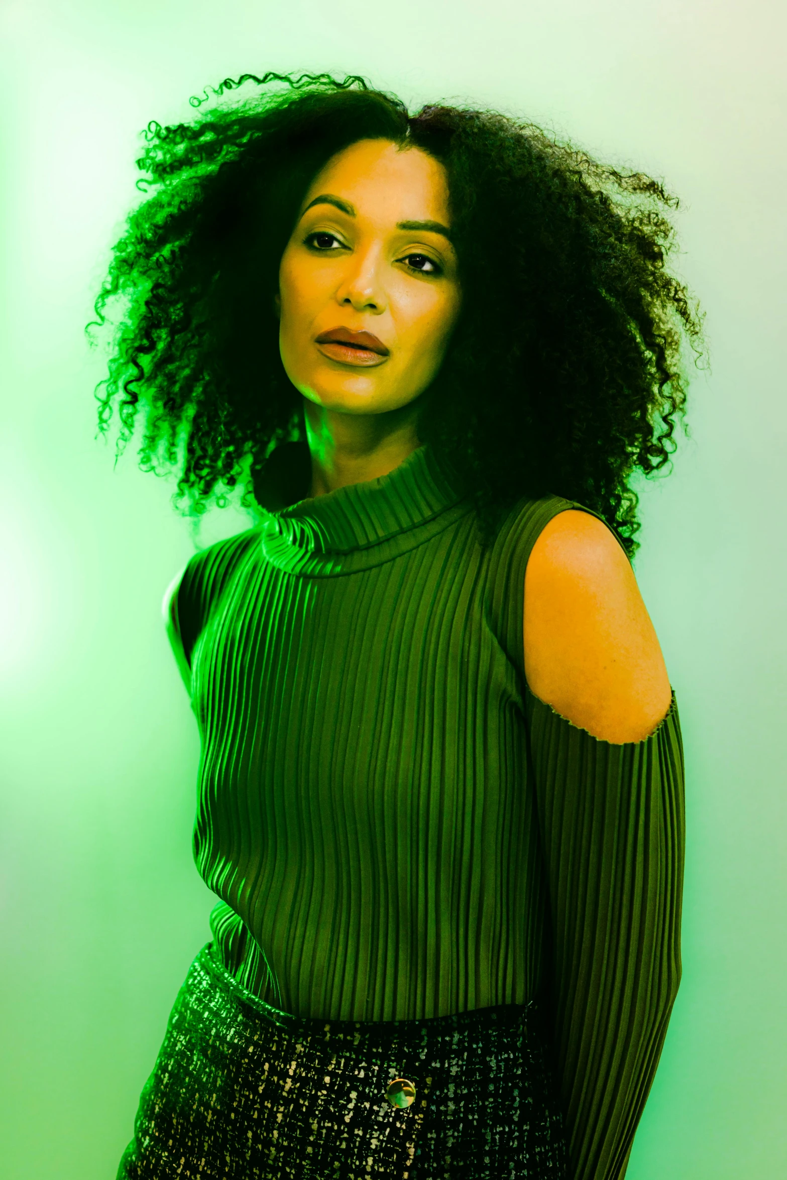 a woman standing in front of green wall wearing a green sweater