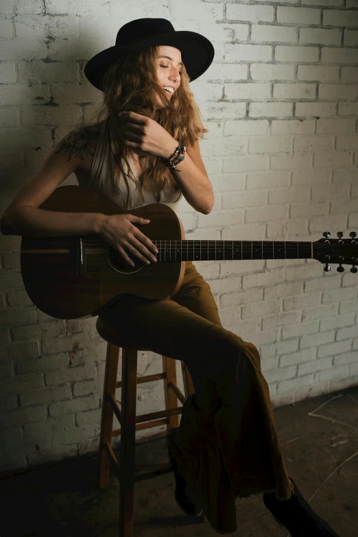 a woman in a cowboy hat and playing guitar