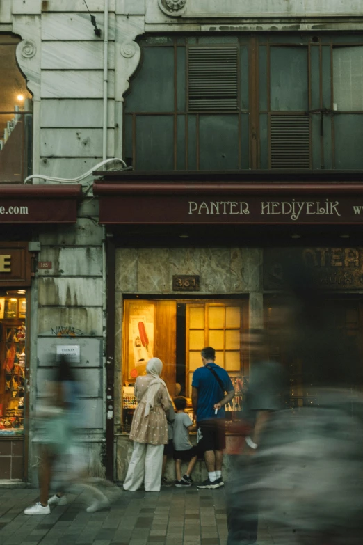 several people outside of a store front and street in the foreground