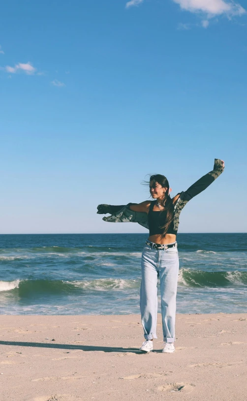 the girl is standing in the sand by the ocean