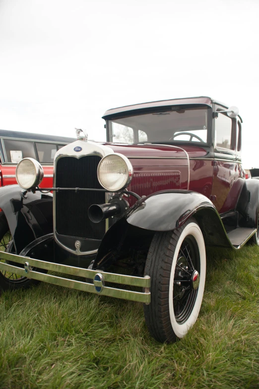 an antique car sits on the grass outside