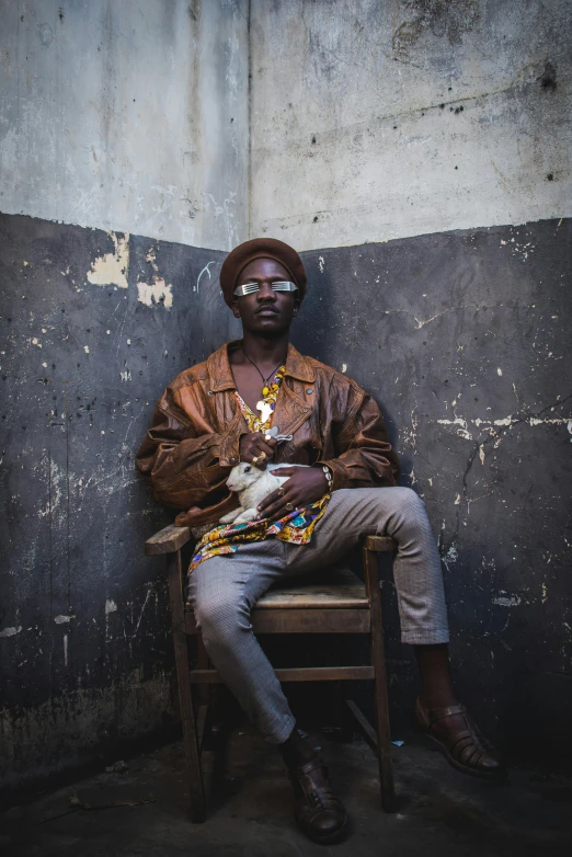 the man is sitting on a chair with a animal in his hand