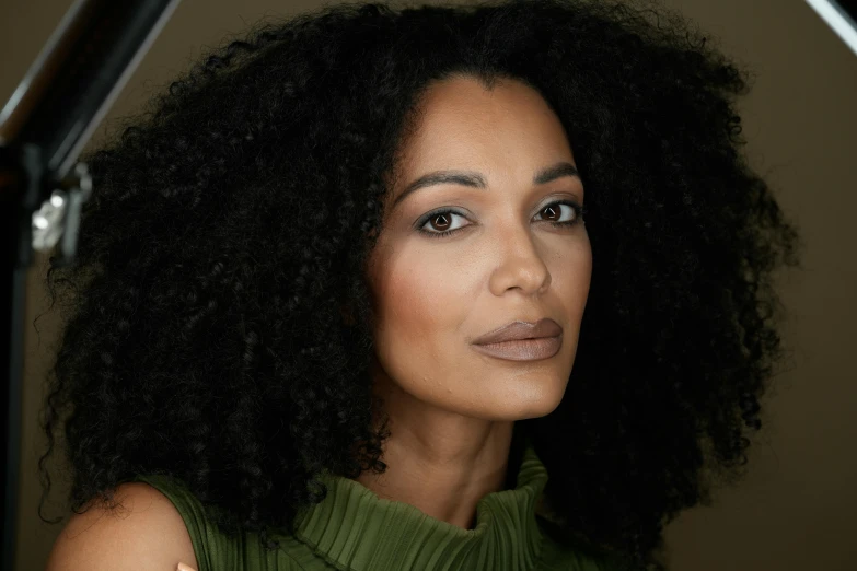 a woman with curly hair is wearing a green dress