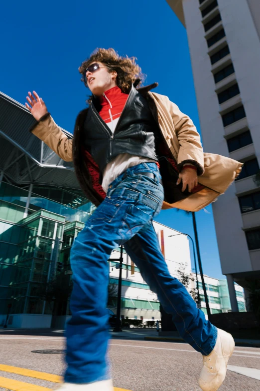 a boy in jeans and leather jacket walking on street