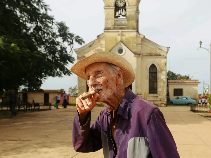 an old man smoking a cigarette outside of a church