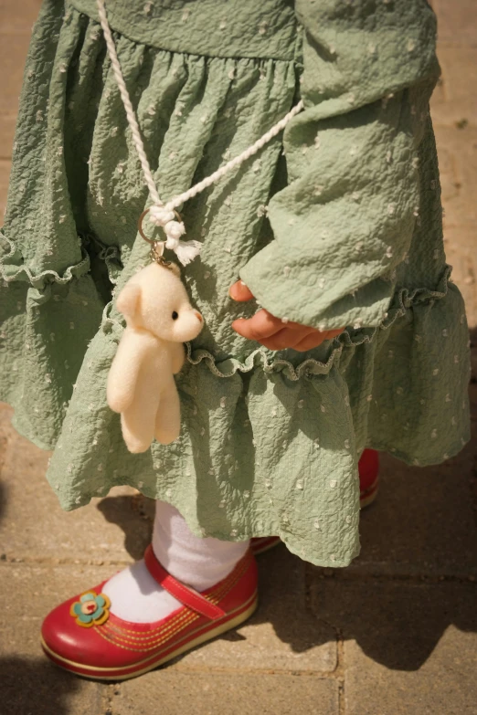 a child with a bear on its hand while wearing a green dress