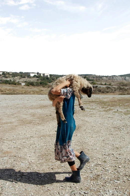 a woman holding a dog in the middle of a desert