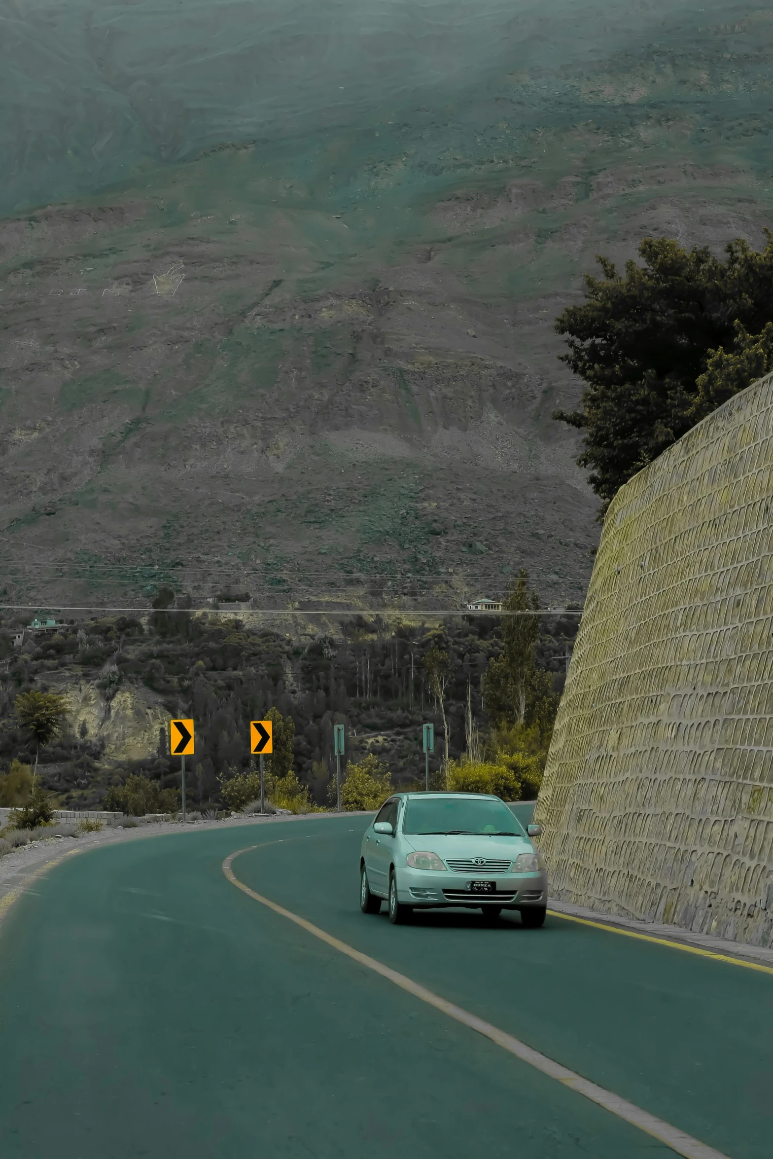 an old fashion car is driving down a road in a valley