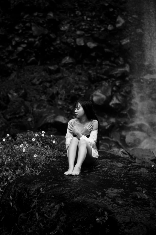 a woman sitting on top of a rock near a waterfall