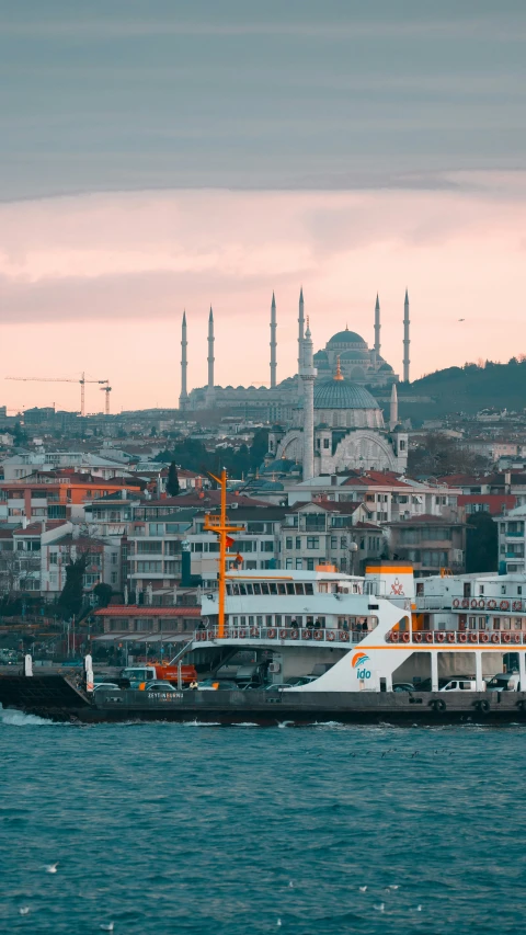 a large ferry in front of a city with the minalis in the distance