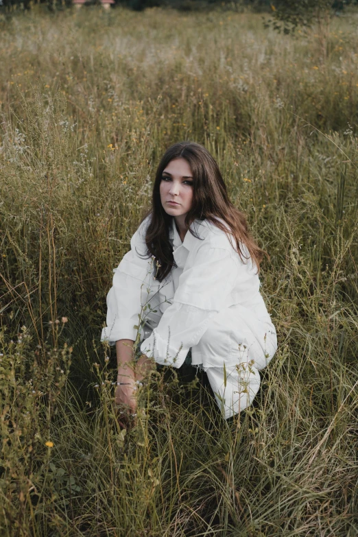 a woman kneeling in a field with her hair tied back