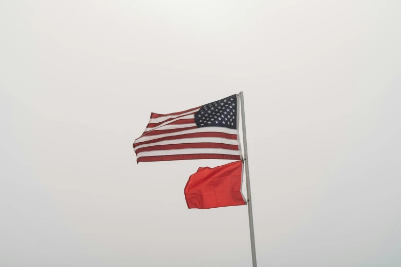 two american flags flying side by side on a cloudless day