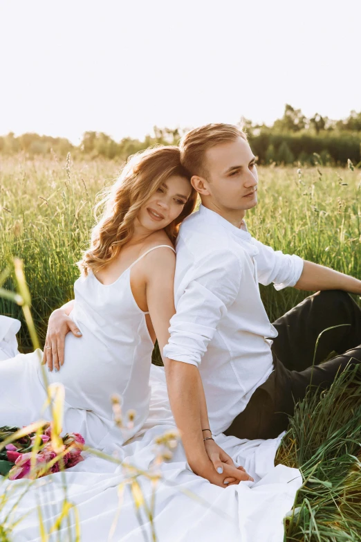 a man and woman are sitting on the grass