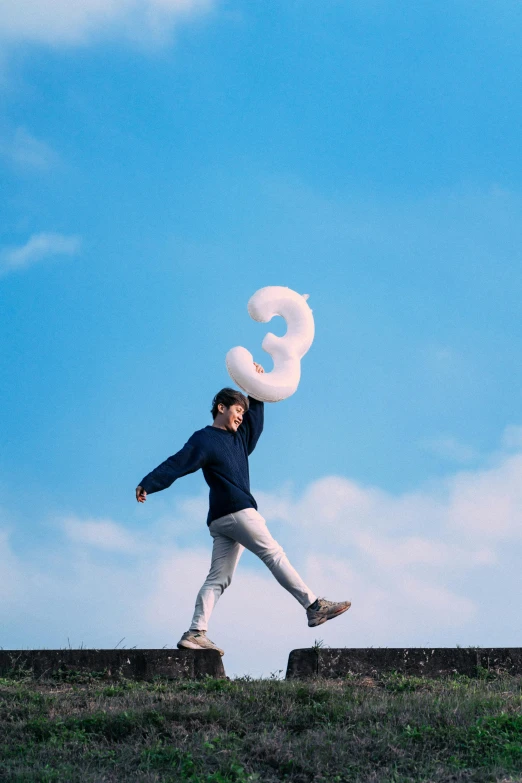 a man standing on the grass, holding two white donuts