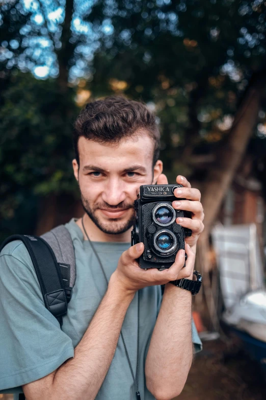 man taking a picture with camera outdoors on a nice day