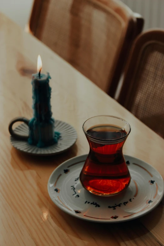 there is a glass cup of tea and a teacup on a plate on the table