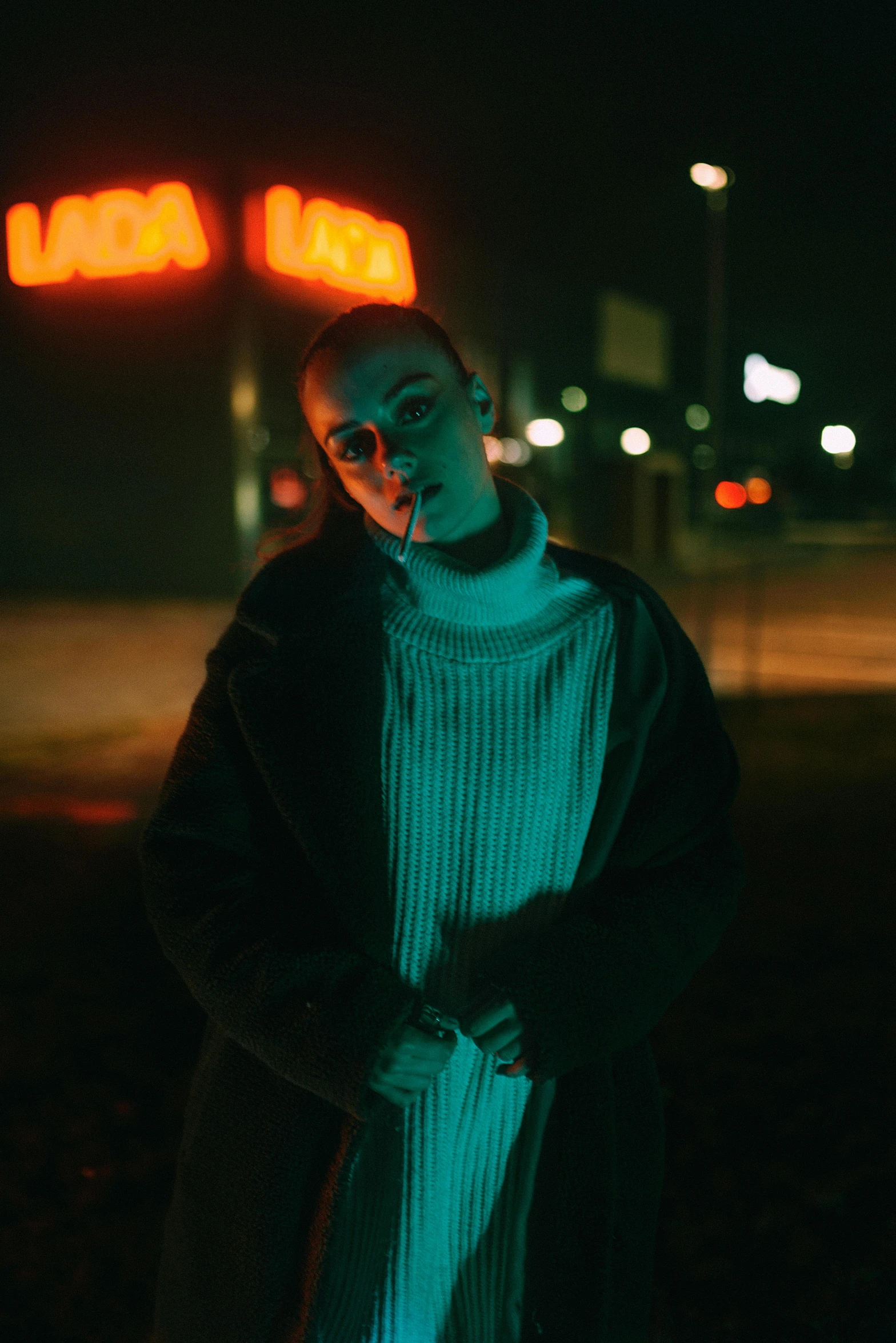 the person is standing outside at night with his head turned towards the camera