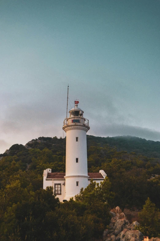 there is a white lighthouse sitting on top of a hill