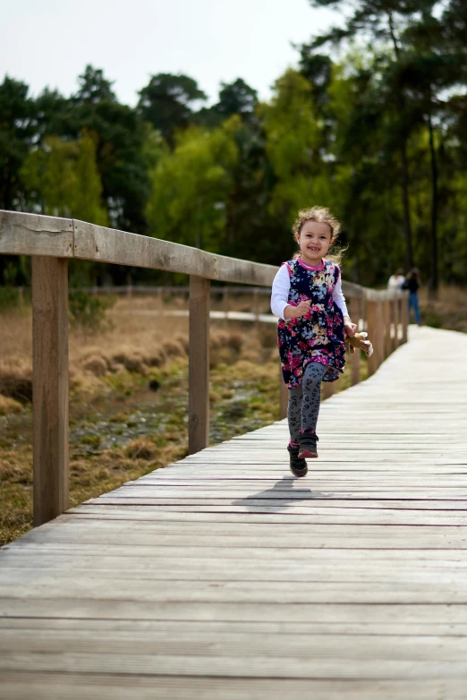 a child is running across a bridge