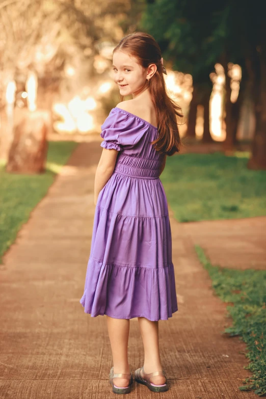 girl wearing purple dress on sidewalk in wooded area