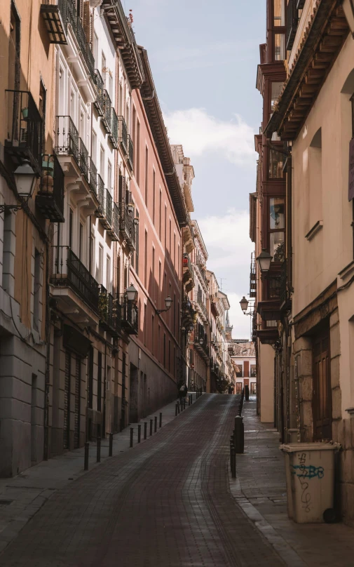 a narrow empty street between buildings with a blue sky in the background