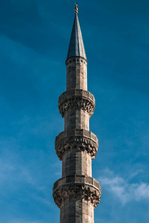 a tower with a pointed roof sits beneath a blue sky