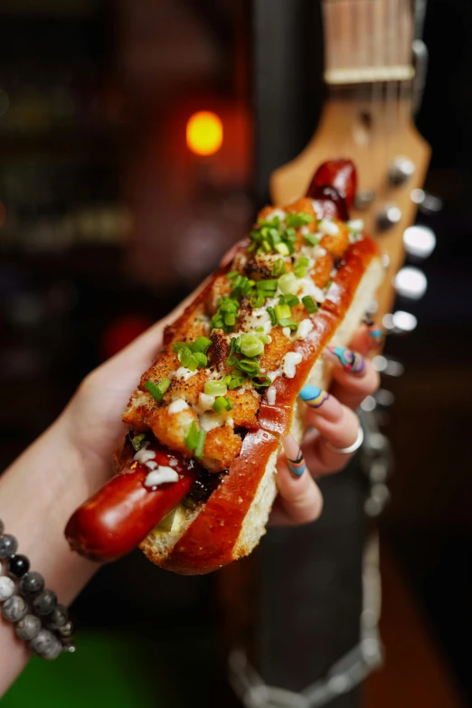 someone holding a sausage with green onions and  dogs